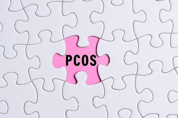 PCOS text on white jigsaw puzzle over pink background. Health Care concept.