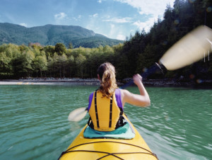 Woman kayaking, swinging paddle in air, blurred motion, rear view
